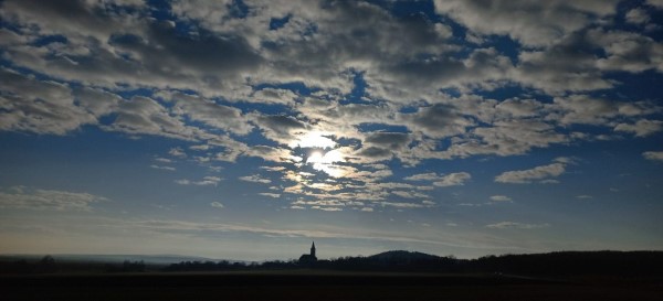 Cludy sky covers the sun over the church of Pécsely